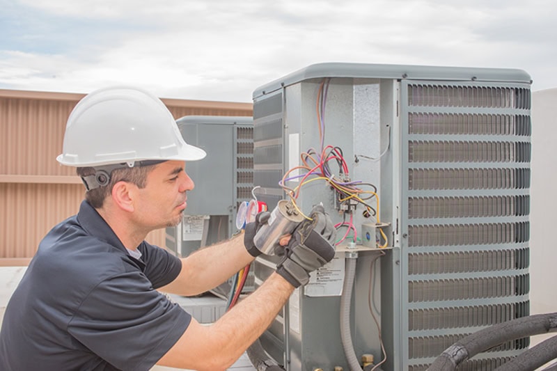 Technician performing HVAC maintenance on rooftop unit in Newfield, New York.