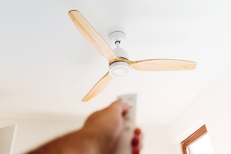 How to Choose the Right Ceiling Fan for Your Space. A person controlling a fan.